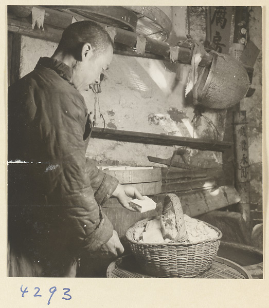 Man filling a basket with tofu in a tofu-making shop