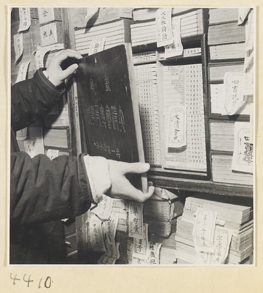 Bookshop interior showing a man holding open the lid of an inscribed wooden case housing a rare edition