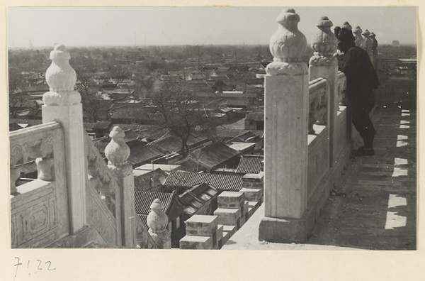 Person leaning on a marble balustrade looking out over rooftops in Beijing