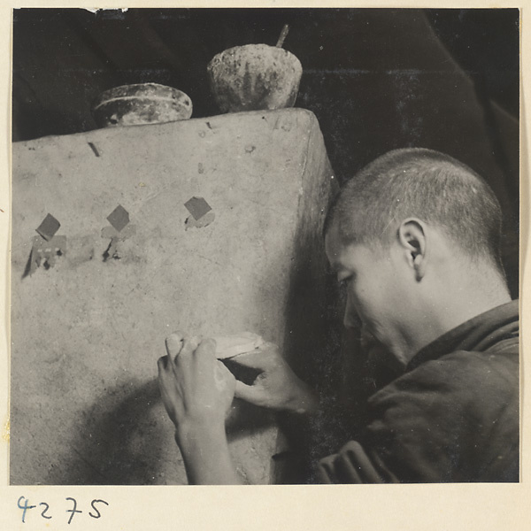 Kitchen interior showing a baker at an oven holding a ma bing