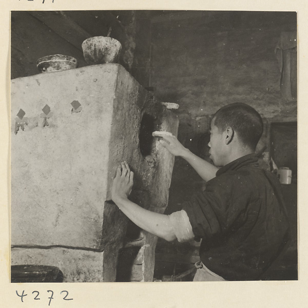 Kitchen interior showing a baker putting a ma bing into an oven