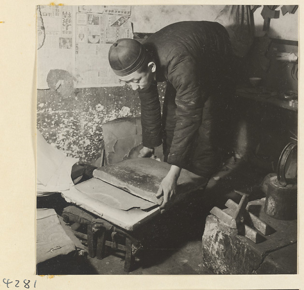 Man working on a piece of cut metal in a metal-working shop