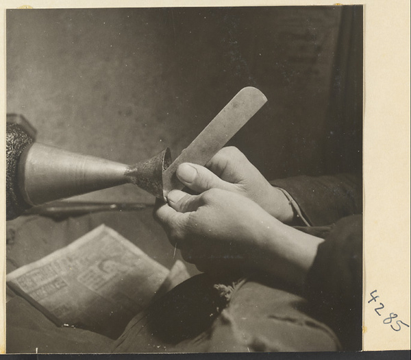 Man at work on a metal vessel in a metal-working shop