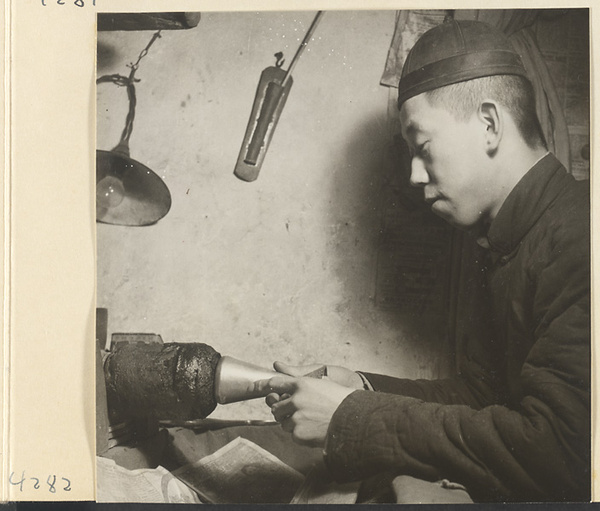 Man at work on a metal vessel in a metal-working shop