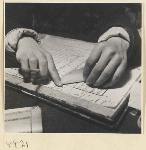 Man patching worm-eaten pages of a book