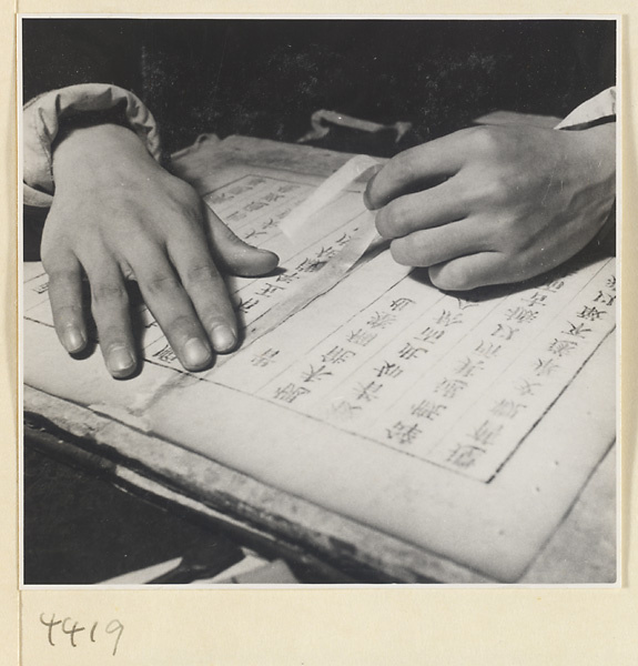 Man repairing damaged pages of a book with rice paper