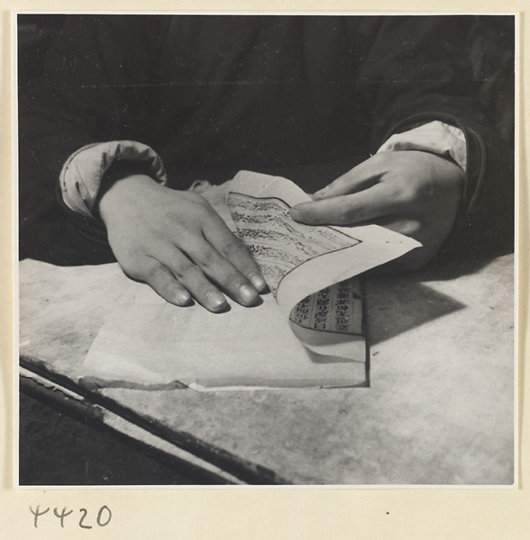 Man strengthening the pages of a book by inserting a protective interleaf