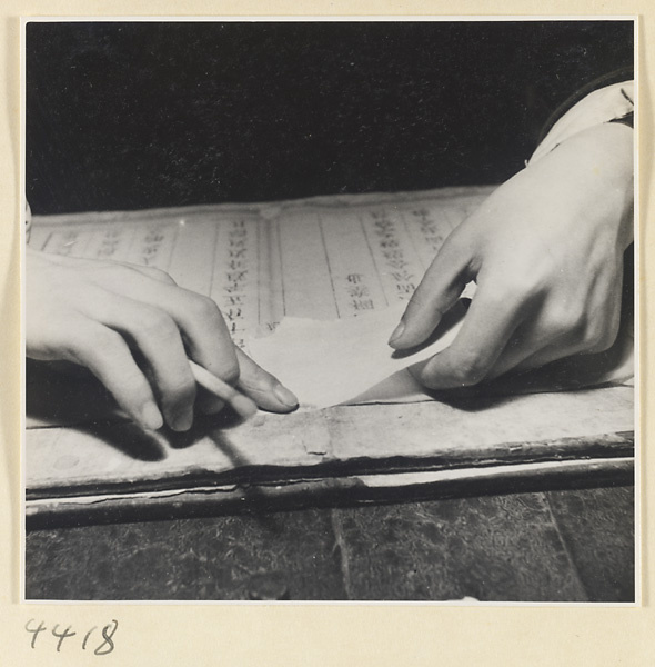 Man repairing damaged pages of a book with rice paper