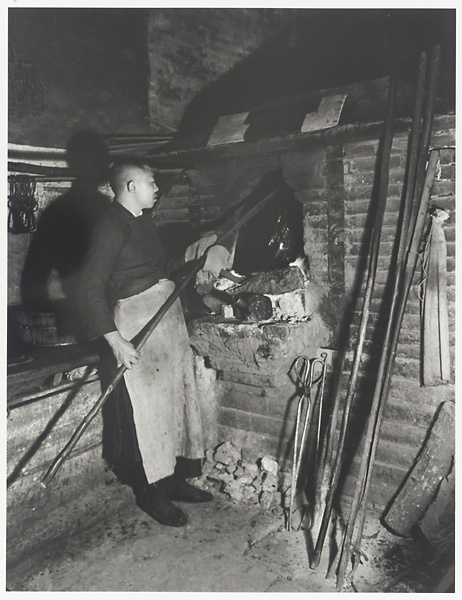 Cook at an oven roasting a Peking duck