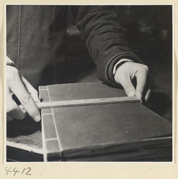 Man measuring the side-sewn binding of a book