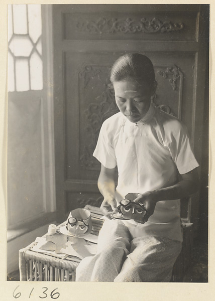 Woman making children's shoes apliquéd with tiger motif