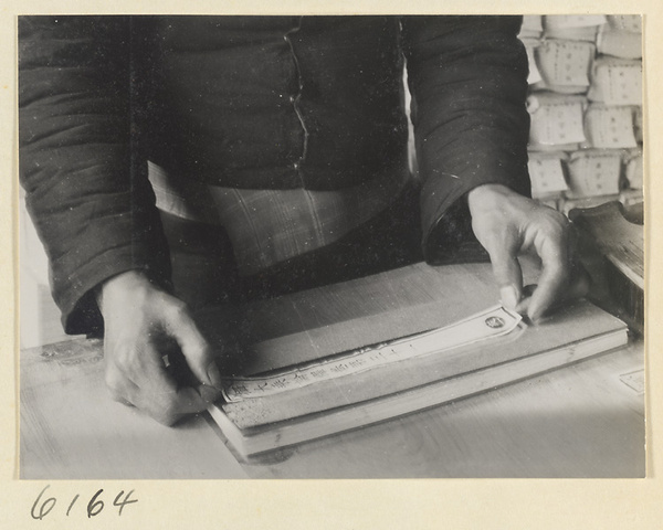 Monk attaching a title to a book in the bindery of a Buddhist temple
