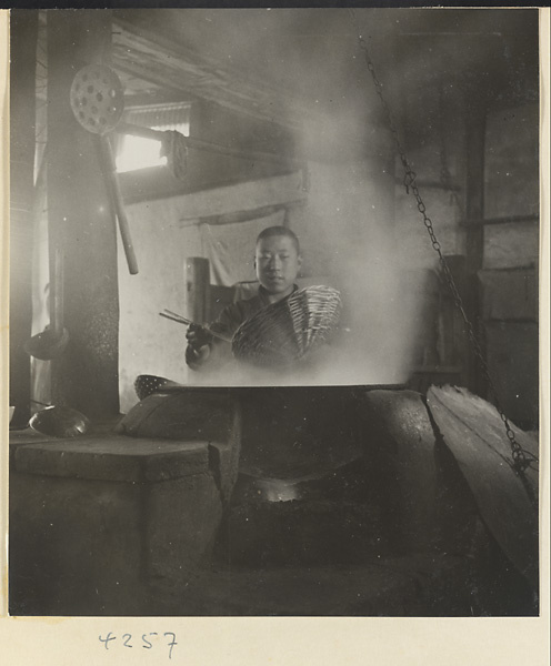 Kitchen interior showing a chef throwing bean cakes into boiling water