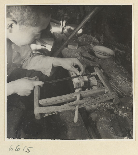 Man using a saw to cut teeth into a comb in a horn-comb workshop