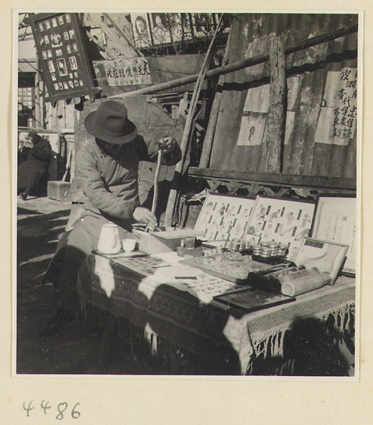 Street doctor holding a snake at his stand displaying medicines and posters picturing ailments