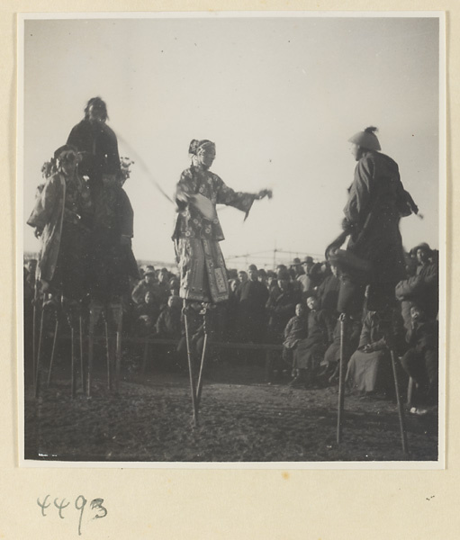 Street entertainers performing on silts in front of a crowd at Tianqiao Market