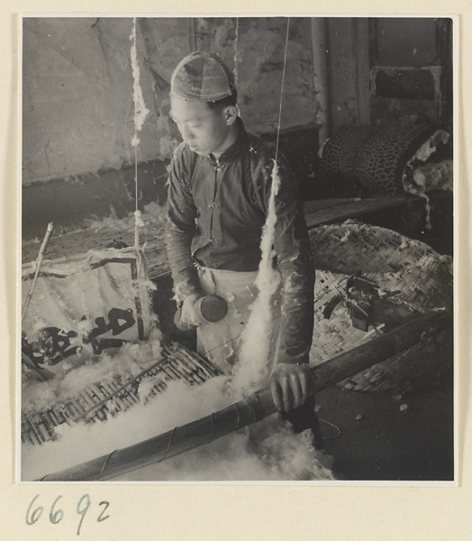 Man preparing cotton for spinning in a workshop