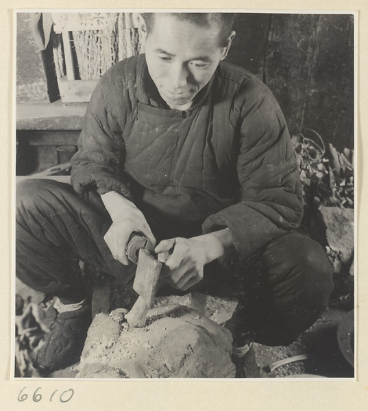 Man cutting a piece of horn with a cleaver in a horn-comb workshop