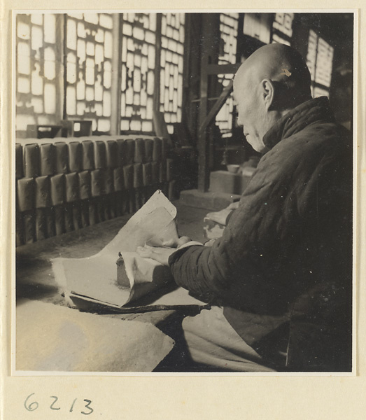 Tobacco shop interior showing a man wrapping a block of pressed tobacco