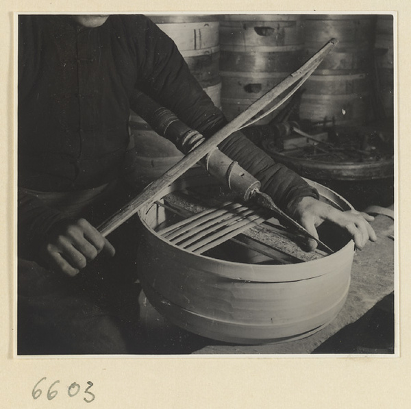 Man drilling holes in the rim of a bamboo steamer in a workshop