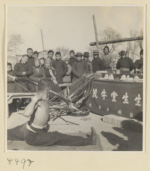 Patent medicine seller of body-building ointments flexing a bow in front of a crowd at Tianqiao Market