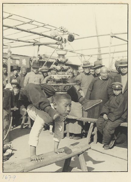 Audience watching boy acrobat performing a balancing act at Tianqiao Market