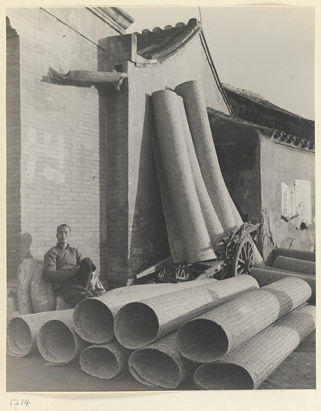Man selling large woven mats outside a shop