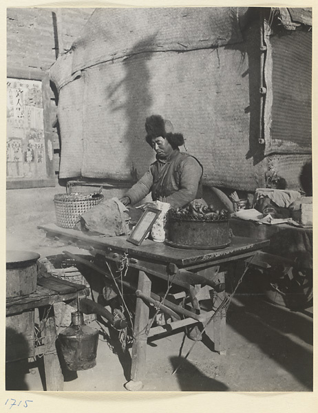 Street vendor selling food at his stand next to a mat shed