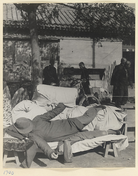 Street vendor taking a nap at his clothing stand