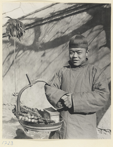 Street vendor hawking cigarettes and candied fruit called tang hu lu from a basket