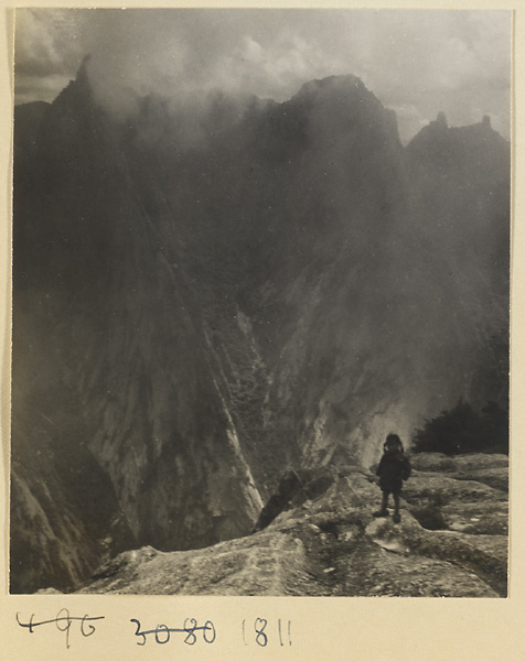 Silhouette of a girl standing on a rock shelf on West Peak of Hua Mountain with Qinling mountains and Guanmao Buttes in background