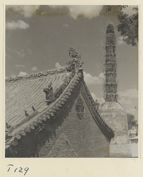 Building detail showing roof ornaments and gable with glazed tile panel (foreground) and storied pagoda (background) at Tai'an