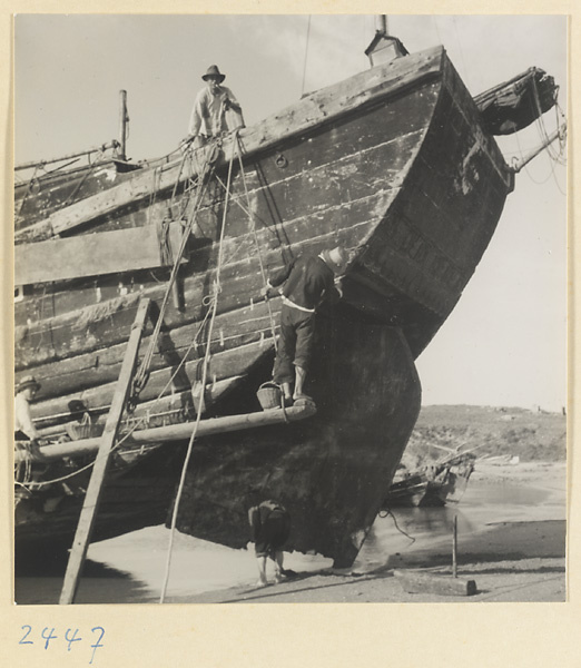 Men working on the hull of a beached fishing junk on the Shandong coast