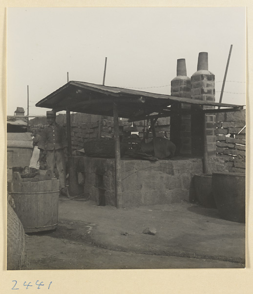 Man standing next to covered stone ovens in a fishing village on the Shandong coast