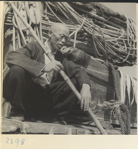 Fisherman with a bamboo pole sitting on a junk on the Shandong coast