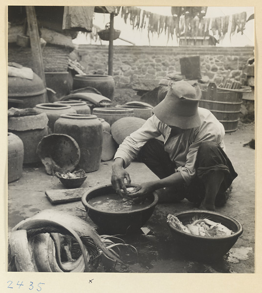 Man at work amidst buckets and vessels in a fishing village on the Shandong coast