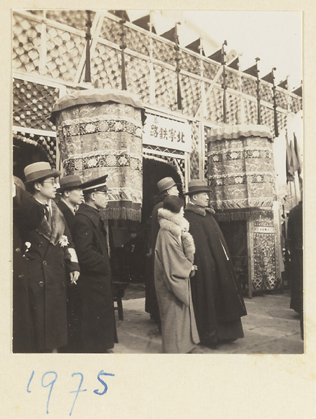 Members of a funeral procession and umbrellas outside a ridged awning erected for the funeral