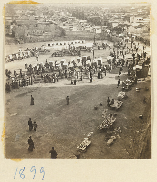 Members of a funeral procession with umbrellas crossing a bridge over a city moat