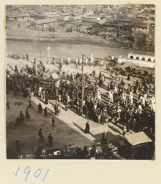 Funeral procession with principal mourners dressed in white preceding coffin and city moat in background