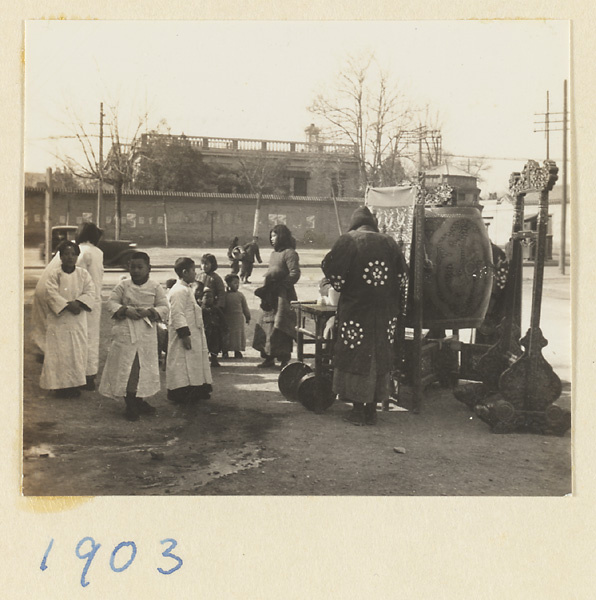 Musician with drum and young snow willow carriers dressed in white waiting for funeral procession