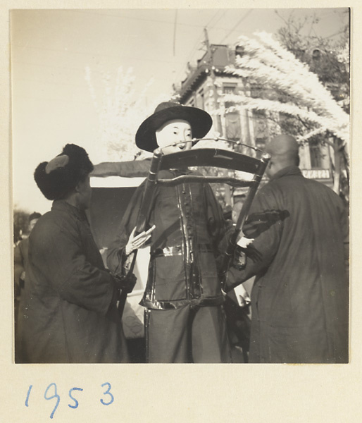 Members of a funeral procession carrying paper figure of a rickshaw puller and paper snow willows