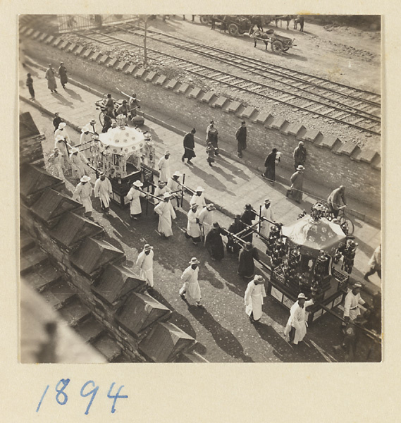 Members of a funeral procession carrying two sedan chairs