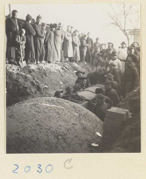 People watching interment of coffin in vaulted brick tomb during funeral