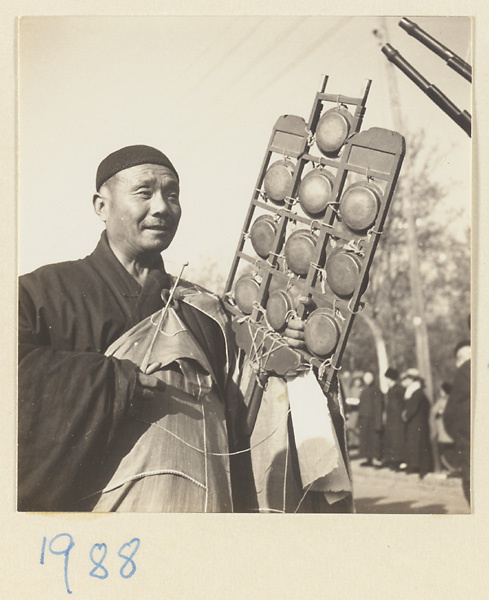 Buddhist monk carrying a yun luo in a funeral procession