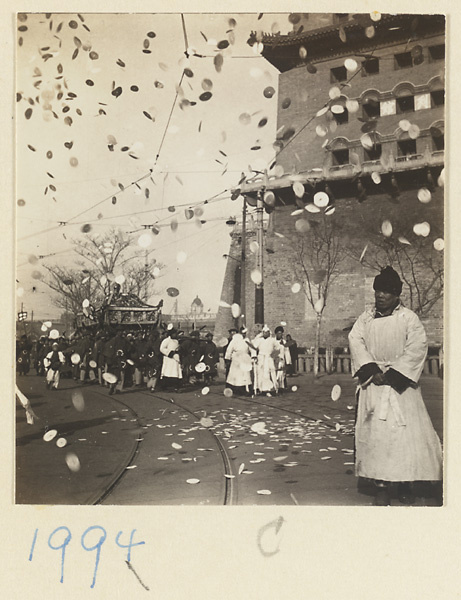 Members of a funeral procession carrying coffin and throwing paper money in the air by Zhengyangmen (正阳门) / Qianmen (前门), Beijing