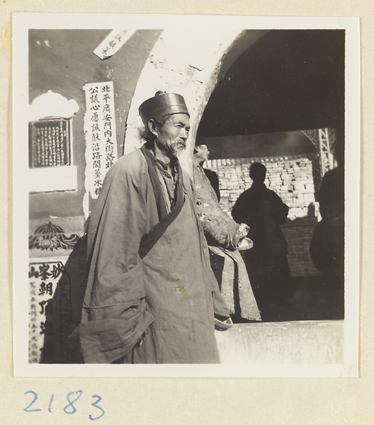 Man standing next to a wall with notices posted on it on Miaofeng Mountain