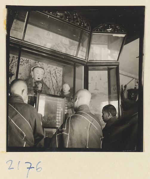 Monks standing at an altar with statues in glass cases inside temple on Miaofeng Mountain