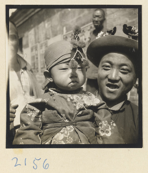 Father and child wearing hats decorated with souvenirs on the pilgrimage trail up Miaofeng Mountain