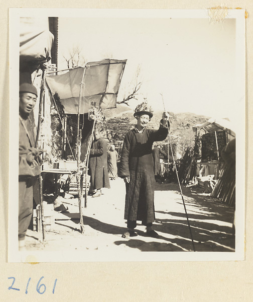 Boy wearing a hat decorated with souvenirs and holding a peach-wood walking stick on the pilgrimage trail on Miaofeng Mountain