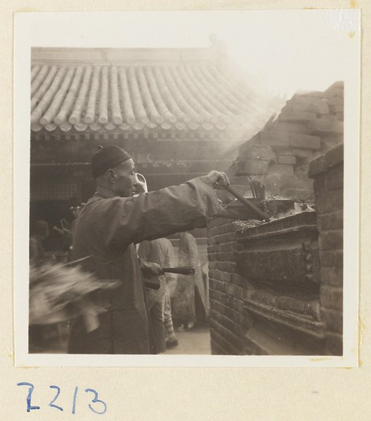 Pilgrim lighting incense at a brick incense burner on Miaofeng Mountain